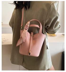 Detailed view of pink pebble leather bucket bag featuring a silk scarf on handle