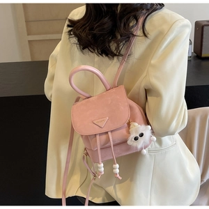 Detail of pink matte backpack with metal logo, drawstring closure and plush pendant