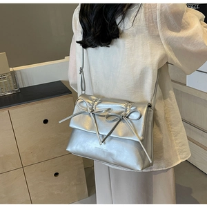Détail d'un sac à bandoulière argenté métallisé avec nœuds et texture matelassée