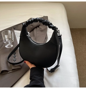 Detailed view of black lychee grain crescent bag with a unique pleated cloud handle