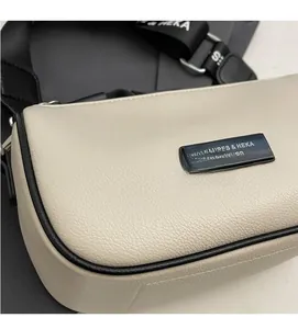 Detail of off-white lychee texture leather handbag with black logo plaque and branded strap