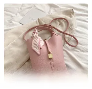 Pink lychee leather bucket bag with silk scarf handle and golden padlock detail
