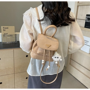Detail of light brown mini backpack with adjustable straps and plush white charm