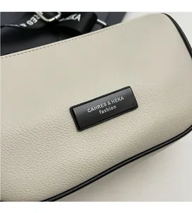 Detailed macro view of cream-colored lychee pattern leather bag with black metal nameplate
