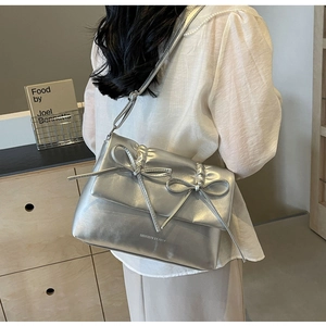 Gros plan d'un sac bandoulière argenté avec double nœud et texture plissée chic