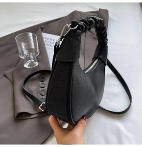 Detail view of the black lychee leather hobo bag featuring a unique ruched top handle