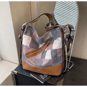 Detail of grey canvas tote bag with brown leather base and adjustable shoulder strap