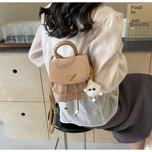 Detail of khaki mini bucket backpack with metal logo plate and plush eye charm
