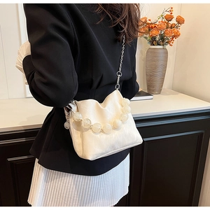 Close-up of beige pleated bucket bag with transparent beaded handle and silver chain