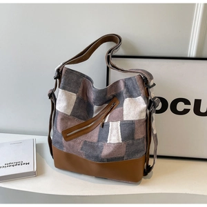 Detail of color-block canvas tote bag featuring diagonal zipper and leather base