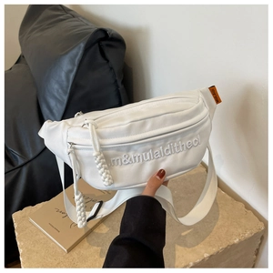 Detail of white matte leather chest bag with orange tag and m&mulaidithecl embroidery