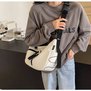 Detailansicht der cremefarbenen Canvas-Tasche mit schwarzem breitem Schultergurt und Schnalle