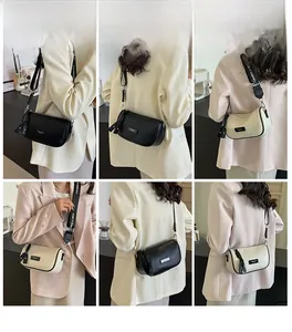 Detail of stylish mini pillow bag with wide branded strap in black and cream leather