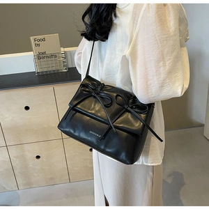 Détail du sac bandoulière noir avec texture plissée et décorations à double nœud