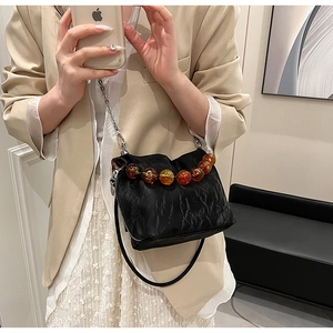 Close-up of black pleated fabric texture and amber resin beads on a stylish handbag