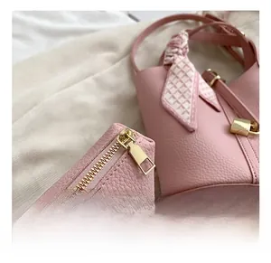Detailed close-up of pink bucket bag with gold hardware zipper and decorative silk scarf