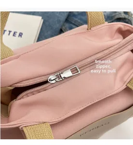 Gros plan sur un cabas en nylon rose avec fermeture éclair argentée et anses tissées beige
