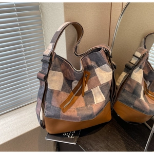Macro view of vintage denim patchwork tote with leather base and metal zipper details