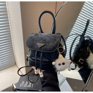 Detail of black velvet mini backpack with drawstring closure and plush monster charm