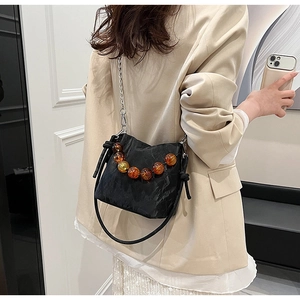 Detail of black pleated bucket bag with amber bead chain and silver metal hardware