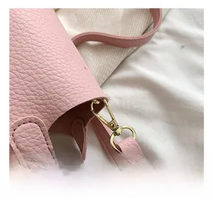 Detailed macro view of pink litchi grain leather bag with gold hardware and stitching