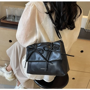 Détail du sac bandoulière noir en cuir souple plissé avec de délicats doubles nœuds