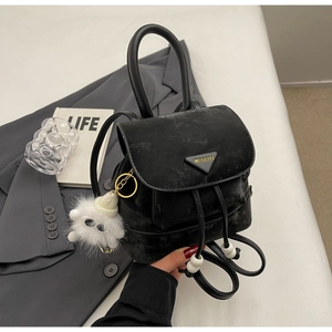 Close-up of black drawstring backpack with metal logo and plush pendant detail