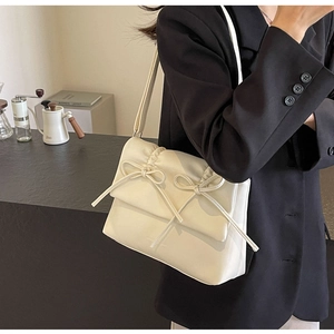 Détail du sac bandoulière plissé crème avec double nœuds sur cuir souple