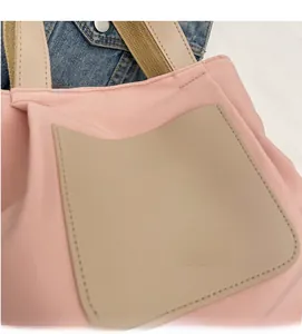 Détail du cabas en nylon rose avec une poche en cuir beige et une texture gaufrée