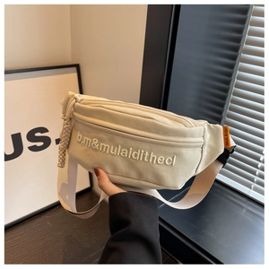 Detailed view of beige canvas waist bag featuring white embroidery and orange brand label
