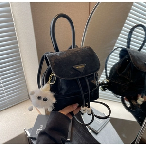Detail of black velvet bucket backpack with drawstring closure and plush pendant
