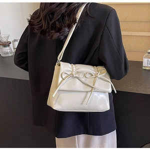 Détail du sac bandoulière crème avec plis délicats, nœuds et texture en similicuir