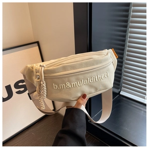 Detailed shot of beige canvas waist bag with white letter embroidery and orange side label