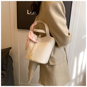 Detail of white lychee leather bucket bag with gold padlock and pink silk scarf wrap