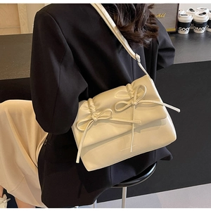 Détail d'un sac bandoulière plissé blanc crème avec décoration de nœud et logo