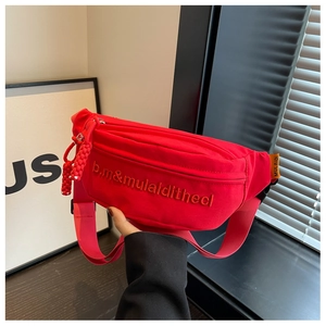 Close-up of red canvas waist bag with letter embroidery and braided zipper pull details