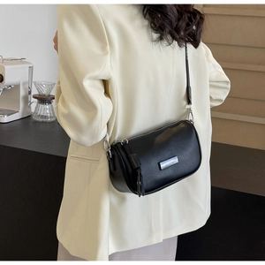 Close-up of black leather crossbody pillow bag with silver hardware on model