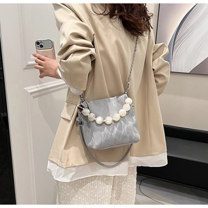 Detail of grey pleated bucket bag featuring pearl bead handle and silver chain strap