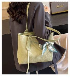 Detail of light green pleated tote bag featuring a decorative silk scarf and thin strap