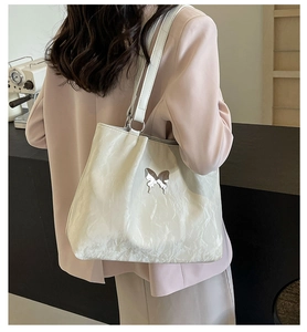 Detailed back view of a white glossy tote bag with a metallic butterfly logo on a model