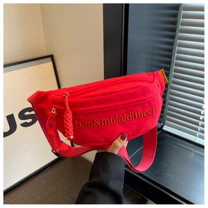 Detail of red nylon waist bag with b.m&mulaidithecl embroidery and orange side label