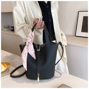 Detail of black lychee leather bucket bag with silk scarf and gold lock hardware