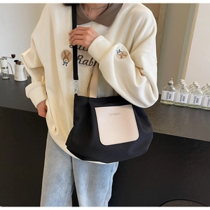 Détail du cabas en nylon noir avec poche en cuir beige et bandoulière en décor intérieur