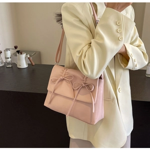 Mannequin portant un sac à bandoulière rose plissé avec nœuds décoratifs sur le rabat