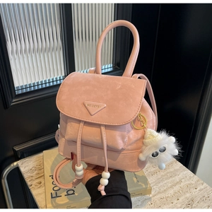 Detail of pink matte leather backpack with triangle logo and white plush monster charm