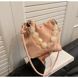Detail of soft pink pleated handbag with large agate-style beaded handle on a book