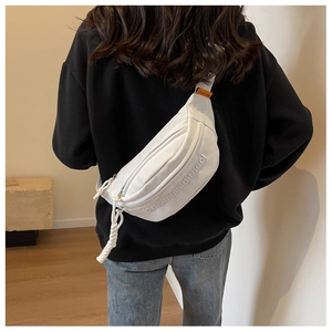 Detailed view of white canvas chest bag with 3D embroidery on a model in a modern room