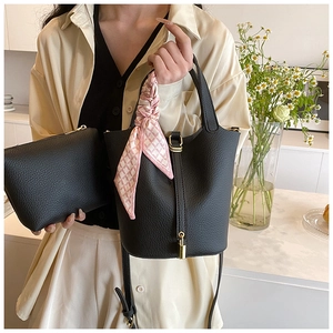 Detail of black lychee grain leather bucket bag with silk scarf and gold lock hardware