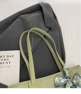 Detail of light green tote bag with decorative fashion scarf and smooth leather strap