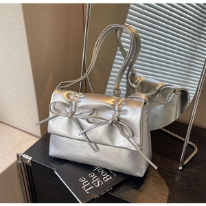 Détail du sac argenté métallisé avec nœuds décoratifs et texture plissée élégante